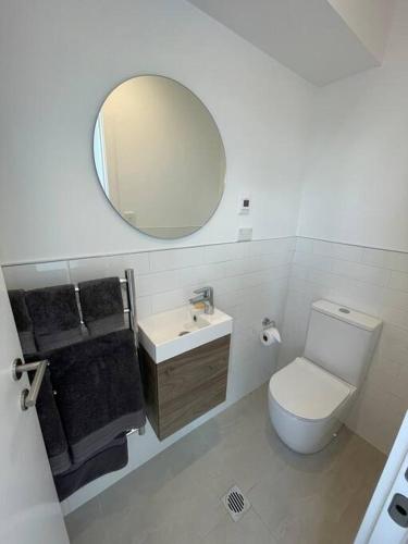 a bathroom with a white toilet and a mirror at Island ambience in the heart of Matakana in Matakana