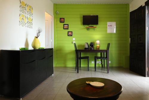 a green room with a table and a tv at Lodges Balourou in Montjoly