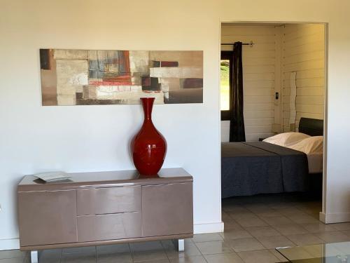 a red vase sitting on a dresser in a bedroom at Lodges Balourou in Montjoly