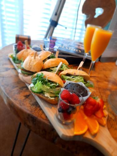 een dienblad met broodjes en fruit op een houten tafel bij Bed & Wellness Angie in Almere