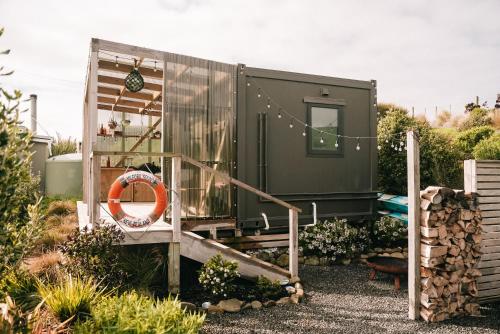 a green tiny house in a garden with an orange ring at Beach Front Oasis - Catlins, Jacks Bay in Hinahina