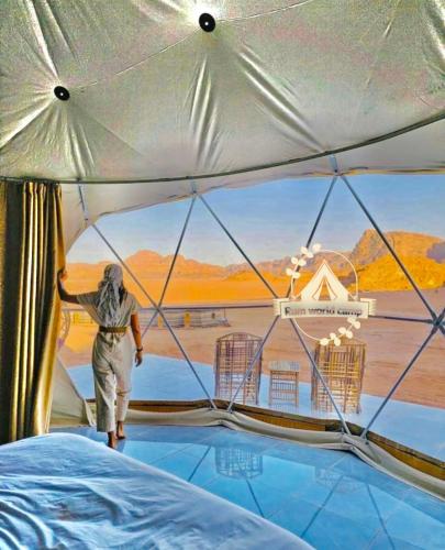 a person walking through a tent with a view at RUM WORLD BUBBLE lUXURY CAMP in Wadi Rum
