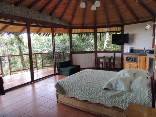 a bedroom with a bed and a kitchen with a balcony at Cascata Del Bosco Cabinas in San Vito