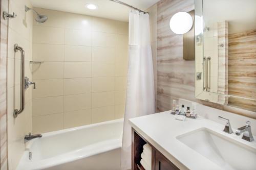 a bathroom with a sink and a tub and a shower at Peoria Marriott Pere Marquette in Peoria
