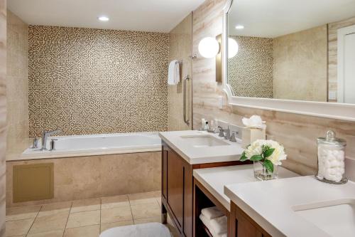 a bathroom with two sinks and a tub and a mirror at Peoria Marriott Pere Marquette in Peoria