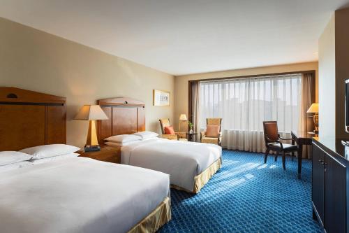 a hotel room with two beds and a desk at Renaissance Tianjin TEDA Convention Centre Hotel in Binhai