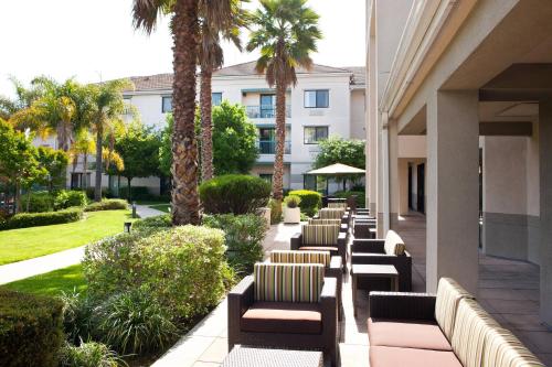 a row of chairs and palm trees next to a building at Courtyard by Marriott Oakland Airport in Oakland