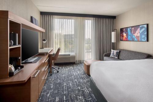 a hotel room with a bed and a desk with a computer at Courtyard by Marriott Philadelphia South at The Navy Yard in Philadelphia