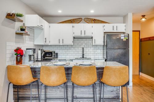 a kitchen with white cabinets and a bar with stools at Walk to Dtwn Winter Park Studio with Hot Tub Access in Winter Park