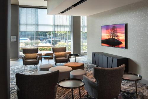 a lobby with chairs and tables and a painting on the wall at Courtyard by Marriott Philadelphia South at The Navy Yard in Philadelphia