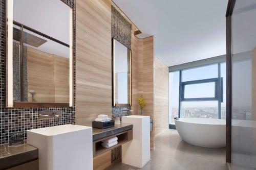a bathroom with a tub and a sink and a mirror at Yancheng Marriott Hotel in Yancheng