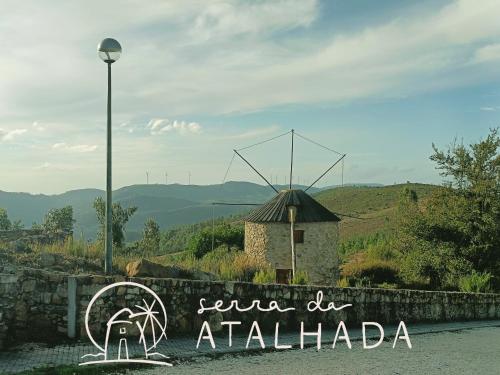 a sign for a restaurant with a windmill in the background at Moinho da Alfazema in Penacova