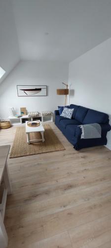 a living room with a blue couch and a table at Escapade en Bretagne in Penmarcʼh