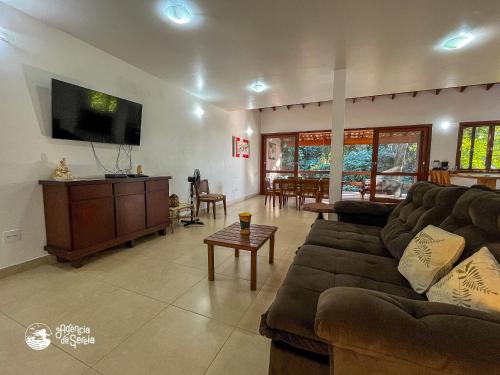 a living room with a couch and a flat screen tv at Casa espaçosa Ilhabela perto da praia das Conchas in Ilhabela