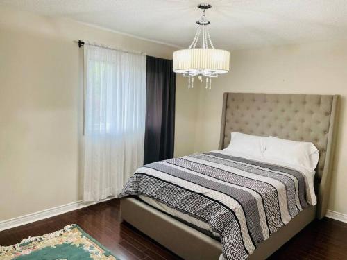 a bedroom with a bed with a chandelier at Luxury 3 bedroom house in Mississauga