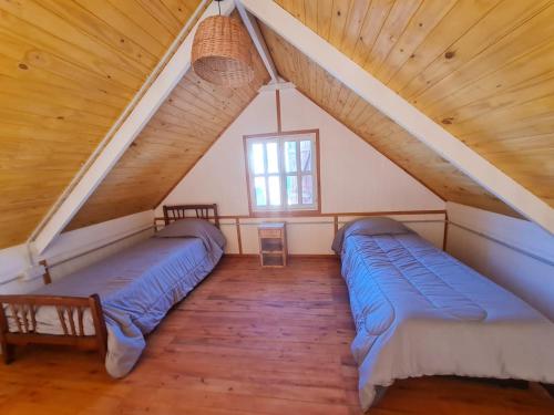 a attic room with two beds and a window at Cabañas Ruidos de Agua in Choele Choel