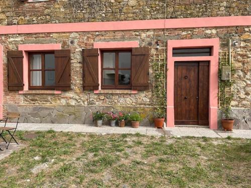 a building with two windows and a door and some plants at Casale de L'Ovo Tuscany Relax in Gabbro