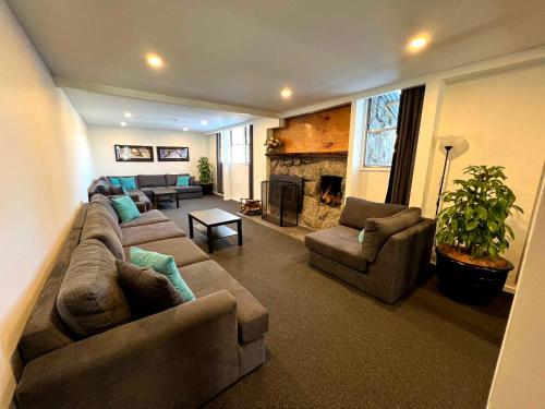 a living room with a couch and chairs and a fireplace at Pipers Lodge in Perisher Valley