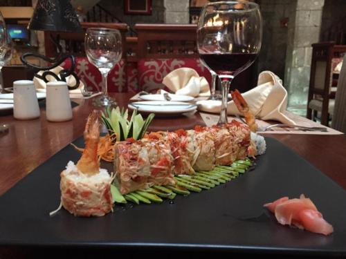 a plate of sushi on a table with wine glasses at Roka Plaza Hotel Boutique in Ambato