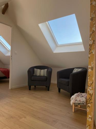 a room with two chairs and a skylight at Les Charmes de Villers in Huchenneville
