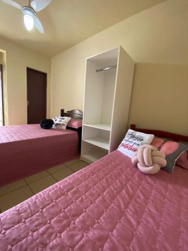 a bedroom with two beds with pink sheets at Pousada Nova in Tramandaí