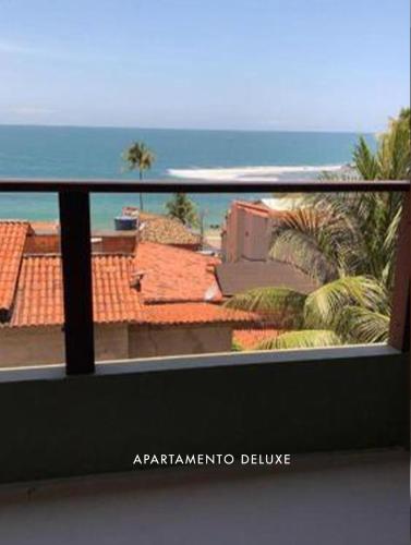 a balcony with a view of the ocean and palm trees at Casas de Juan in Morro de São Paulo