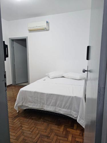 a bedroom with a white bed with a wooden floor at CIG Hostel in Goiânia