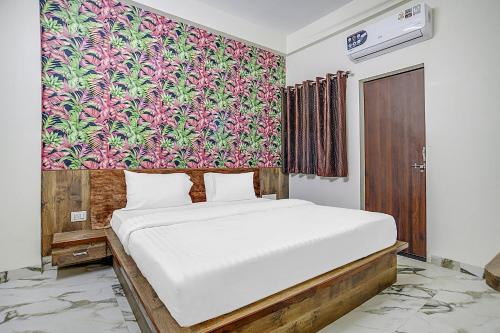 a bedroom with a white bed with a colorful wall at Collection O Verena in Indore