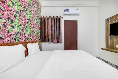 a bedroom with a white bed and a colorful wall at Collection O Verena in Indore