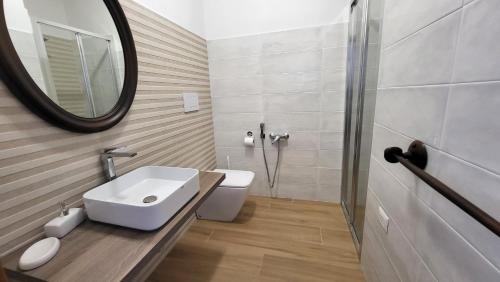 a bathroom with a sink and a toilet and a mirror at Villa Andres in Sassari