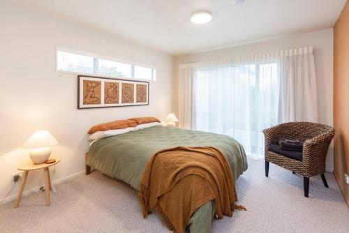 a bedroom with a bed and a chair and a window at On Cotswolds in Whanganui