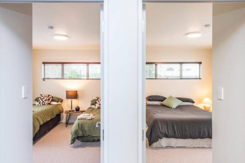 a bedroom with two beds and a mirror at On Cotswolds in Whanganui