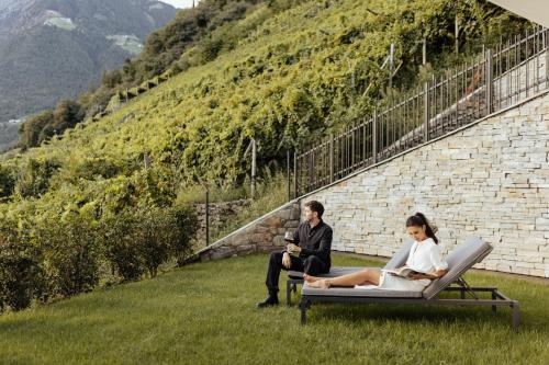 a man and woman sitting on a lounge chair in the grass at The Hills Merano in Merano