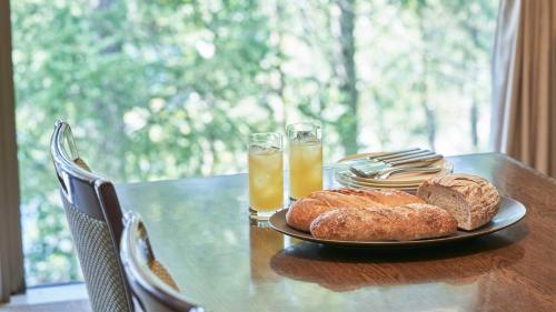 a table with a plate of bread and two glasses of orange juice at Tokyu Vacations Tateshina in Chino