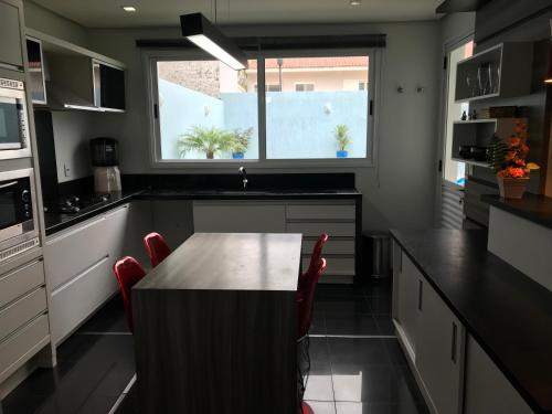 a kitchen with a wooden table and red chairs at Conforto entre a UFSM e o centro in Santa Maria