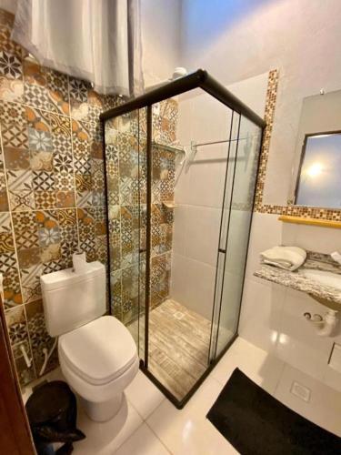 a bathroom with a toilet and a glass shower at Flats Paz in Itacaré