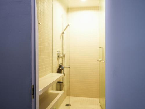 a bathroom with a shower and a sink at Rembrandt Cabin Shinjuku Shin-Okubo in Tokyo