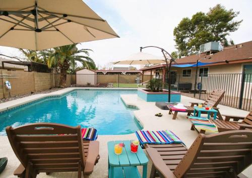 a swimming pool with chairs and a table and an umbrella at Tranquil Mesa Retreat in Mesa