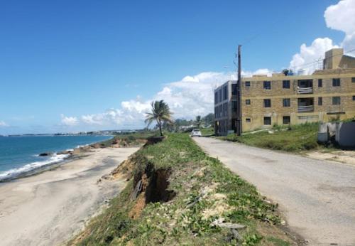 a dirt road next to a beach with a building at Vacation Rental Arecibo PR in Arecibo