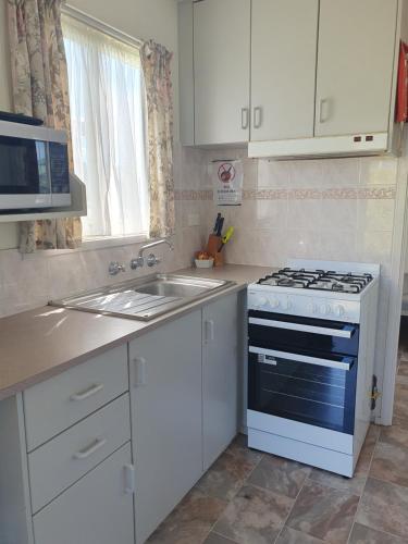 a white kitchen with a stove and a sink at North Arm Tourist Park in Lakes Entrance