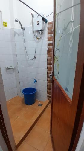 a bathroom with a shower and a blue bucket at Amara Transient - 2 Bedroom Apartment in Tuding