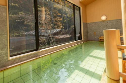 a swimming pool in a room with a large window at Shionoyu Onsen Rengetsu in Nasushiobara