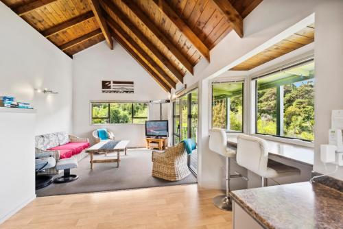 a kitchen and living room with white walls and windows at Opahi TreeHouse - Mahurangi West Holiday Home in Warkworth