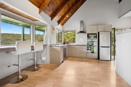 a kitchen with white appliances and large windows at Opahi TreeHouse - Mahurangi West Holiday Home in Warkworth