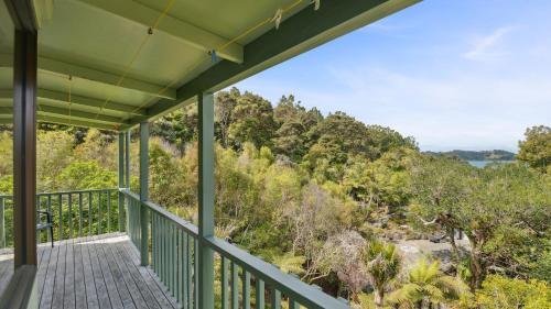 a house with a green porch with a view of the forest at Opahi TreeHouse - Mahurangi West Holiday Home in Warkworth