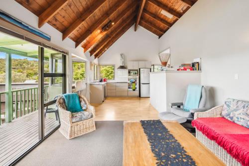a living room with a red couch and a kitchen at Opahi TreeHouse - Mahurangi West Holiday Home in Warkworth