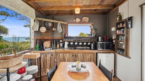 a kitchen with a table and a view of the ocean at Tawharanui Cabin - Rural Cabin Studio in Warkworth