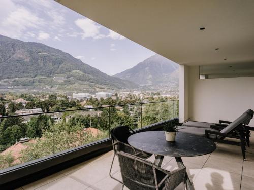 a balcony with a table and chairs and mountains at The Hills Merano in Merano