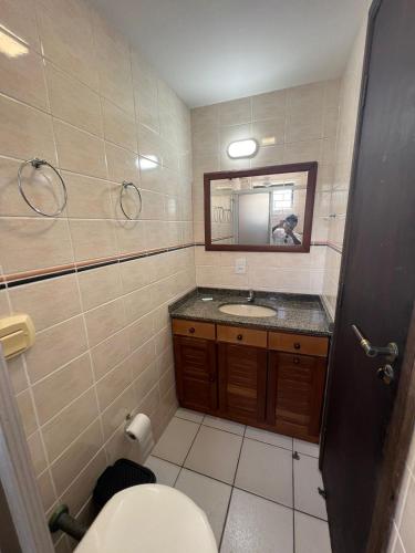 a bathroom with a toilet and a sink and a mirror at Triplex White em Caiobá-Matinhos-Pr a 200 mt do mar in Matinhos
