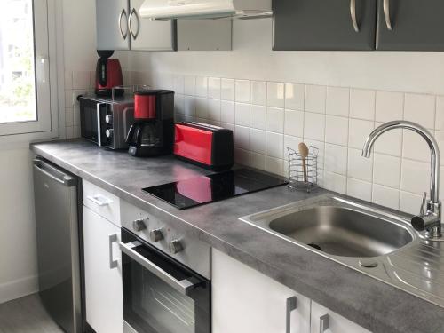 un comptoir de cuisine avec un évier et un micro-ondes dans l'établissement Appartement avec balcon, proche CHU, château, Tramway, à Angers